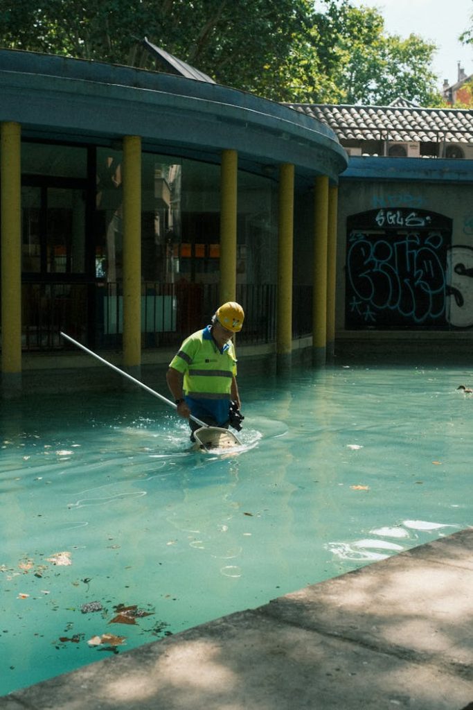 pexels-photo-21327976 A pool maintenance worker wearing safety gear cleans an outdoor pool in Barcelona, Spain.